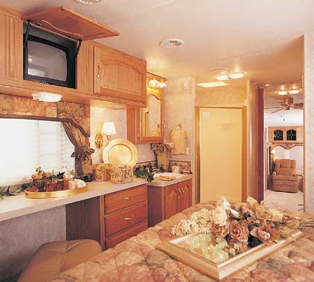 The 34.5 RLTG in Spice Decor. Full dresser with desk/vanity area, optional TV in overhead cabinets, easy step in corner shower with glass door and lighted medicine cabinet with mirrored doors.